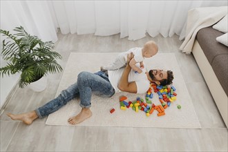 High angle father playing floor home with baby