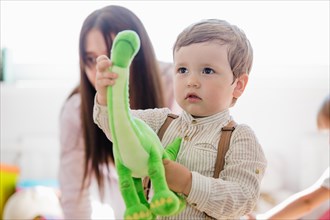Little boy holding green dinosaur toy