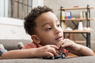 Thoughtful black boy playing with toy car