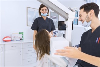 Male dentist scanning female patient s teeth with x ray machine