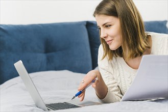 Woman with papers browsing laptop