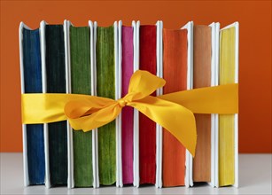 Rainbow books stack with yellow ribbon