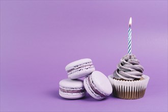 Macaroons near cupcake with candle