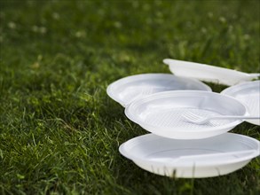 Close up white plastic plate fork grass park