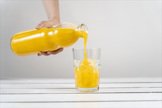 Close up hand pouring orange juice glass