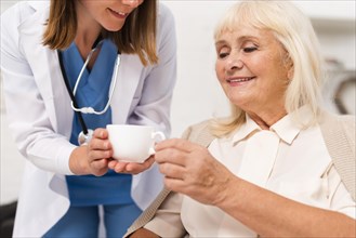 Nurse giving tea old woman close up