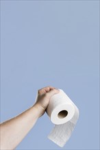 Front view hand holding toilet paper with copy space