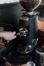 Crop hands grinding coffee into portafilter