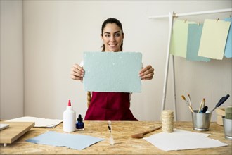 Smiling woman holding handmade blue paper