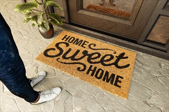 Home sweet home doormat and shoes of a man standing on the porch at the front door