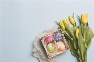Box with eggs near tulips blue