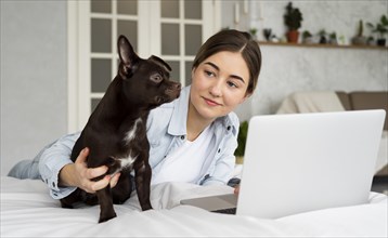 Medium shot teen bed with laptop dog