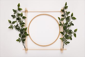 Wooden square circle frame decorated with green leaves white backdrop