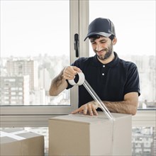 Smiling delivery man uniform packing cardboard box