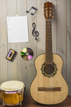 Blank musical page cassette compact disc musical note stuck wooden wall with guitar bongo drum