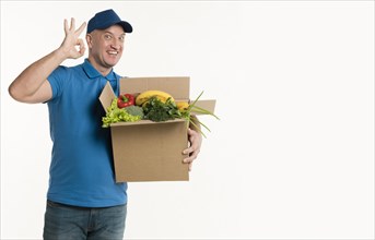 Delivery man holding grocery box showing okay sign