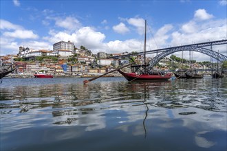 View over the traditional Rabelo boats on the Douro riverbank in Vila Nova de Gaia towards the old town of Porto and the bridge Ponte Dom Luis I