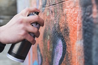 Man s hand drawing graffiti wall with aerosol can