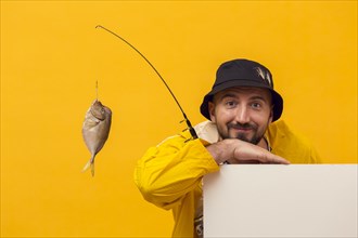 Front view fisherman posing while holding fishing rod with catch