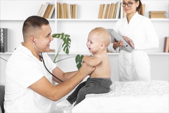 Young doctor listening adorable baby with stethoscope