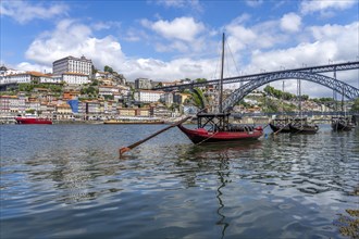 View over the traditional Rabelo boats on the Douro riverbank in Vila Nova de Gaia towards the old town of Porto and the bridge Ponte Dom Luis I