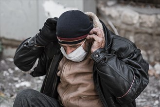 Front view homeless man outdoors putting medical mask