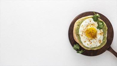 Flat lay pita with avocado spread fried egg with cutting board