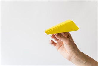 Hand holding yellow paper plane
