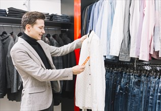 Young man shop checking price tag shirt