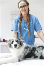 Portrait female veterinarian with dog lying table clinic
