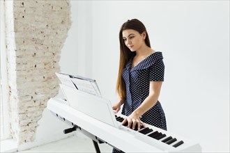 Portrait young woman looking musical sheet playing piano