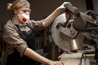 Side view female carpenter using round saw