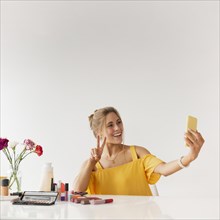 Woman taking selfie while showing sign peace