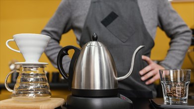 Front view male barista with apron preparing coffee with kettle filter