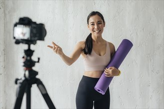 Smiley vlogger holding fitness mat