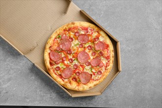 Top view of pizza with sausage and colorful bell pepper in cardboard box