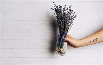 Close up person holding lavender bouquet against wooden backdrop