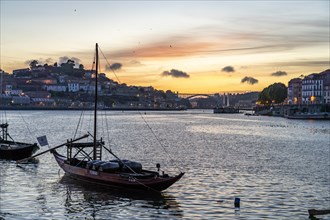 Rabelo boats loaded with port wine barrels on the banks of the Douro at sunset