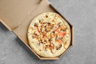 Pizza with chicken breast and champignon mushrooms in cardboard box