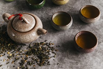 Chinese brown teapot teacups with tea herbs concrete backdrop