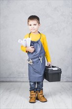 Cute boy standing with tool box paper rolls
