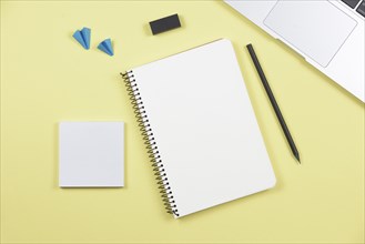 Laptop pencil spiral notebook adhesive notepad airplane eraser yellow background