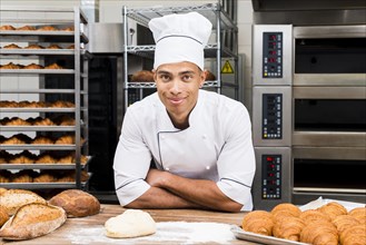 Portrait smiling young male baker standing table with fresh croissant loaf bread