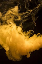Yellow bright smoke clouds spread out wide against dark black background