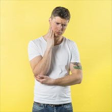 Sad young man having toothache against yellow background
