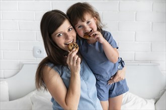 Mother daughter eating chocolate cookies