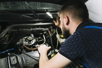Repairmen inspecting vehicle engine