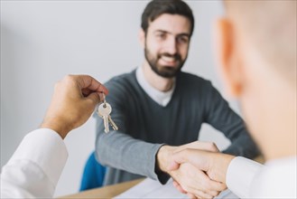 Real estate agent shaking hand client holding keys