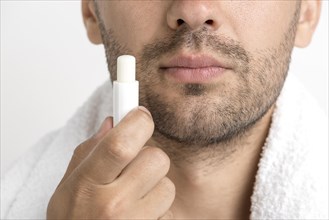 Lose up man with towel around his neck holding lip balm