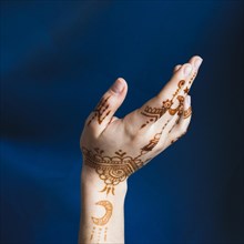 Hand with mehndi near blue textile